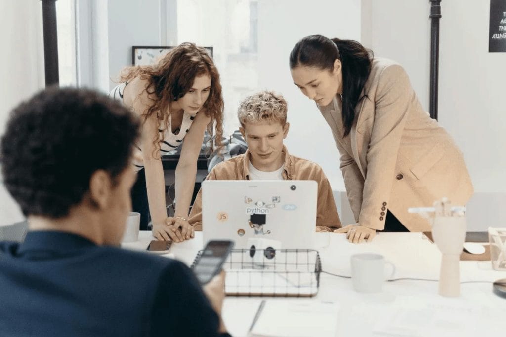 Group of young professionals gathered around a laptop, collaborating on a project.