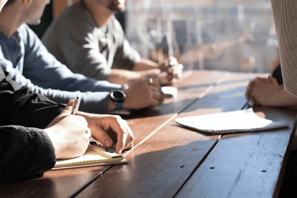 Close-up of team members taking notes during a meeting.