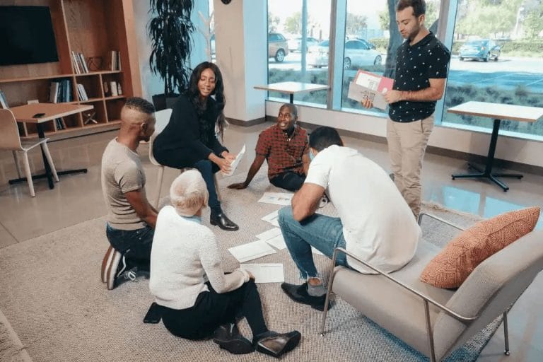 Colleagues engaged in a brainstorming session, seated on the floor and a sofa.