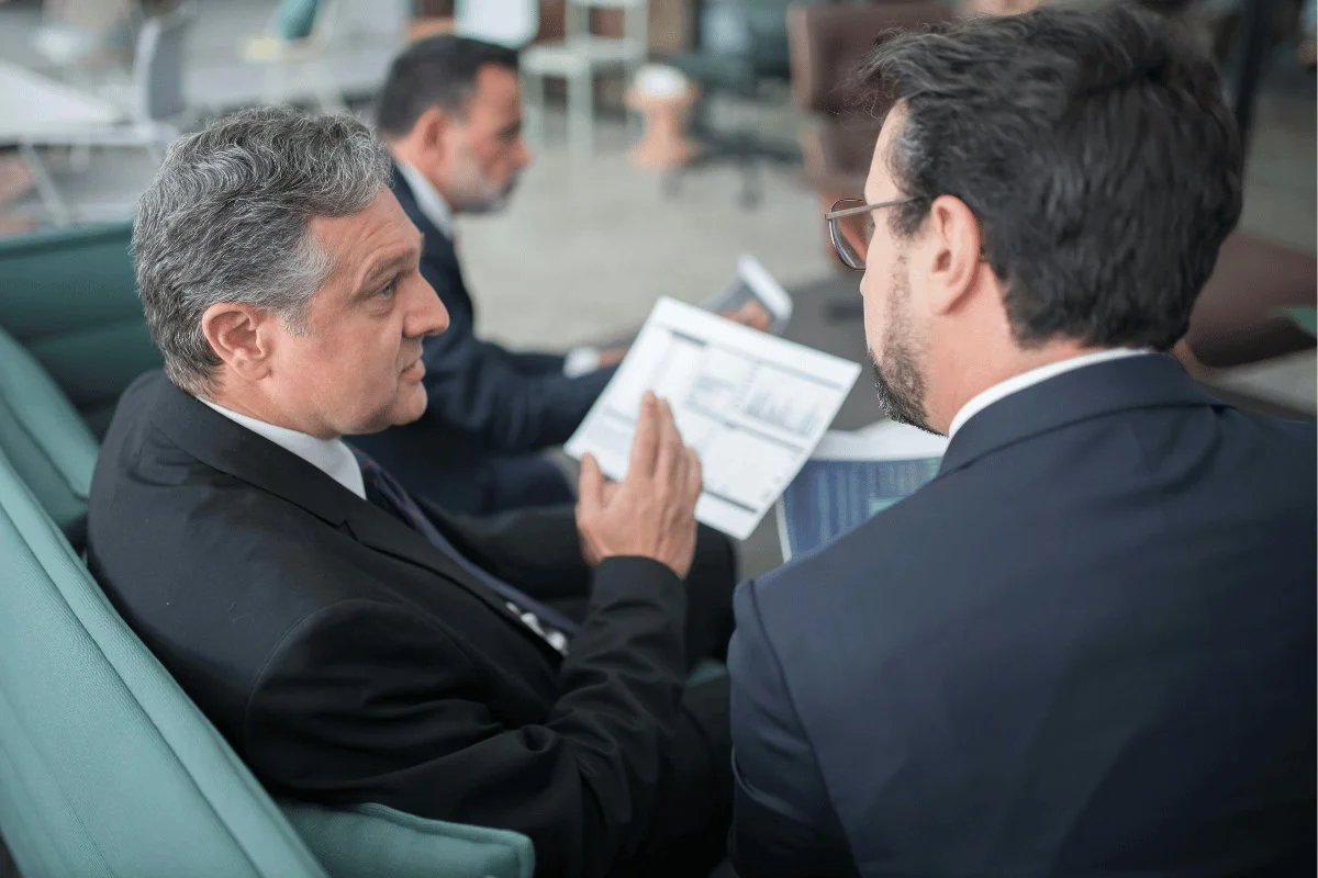 Businessmen discussing data charts in a modern office lounge.