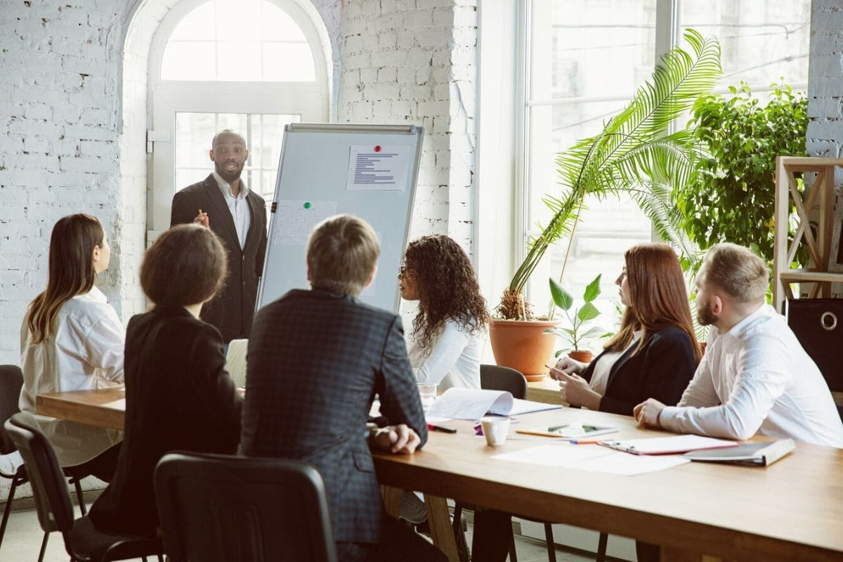 Man in a suit presenting to colleagues during a business meeting.