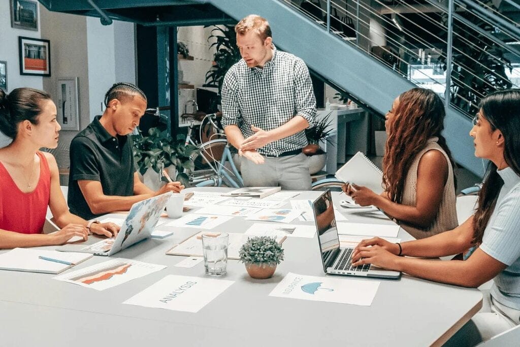 Man presenting data to coworkers in a meeting room.
