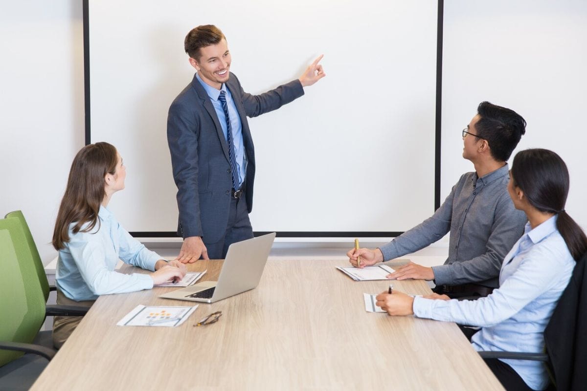 Four individuals having a meeting in a well-lit conference room.