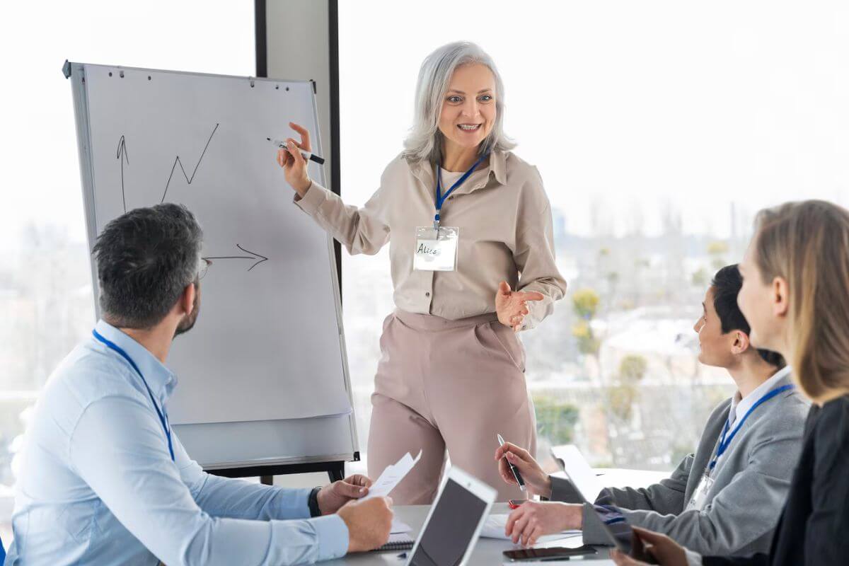 Businesswoman presenting data on a whiteboard to a team.