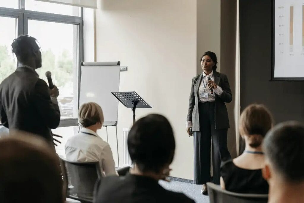 Female speaker presenting to an engaged audience at a business seminar.