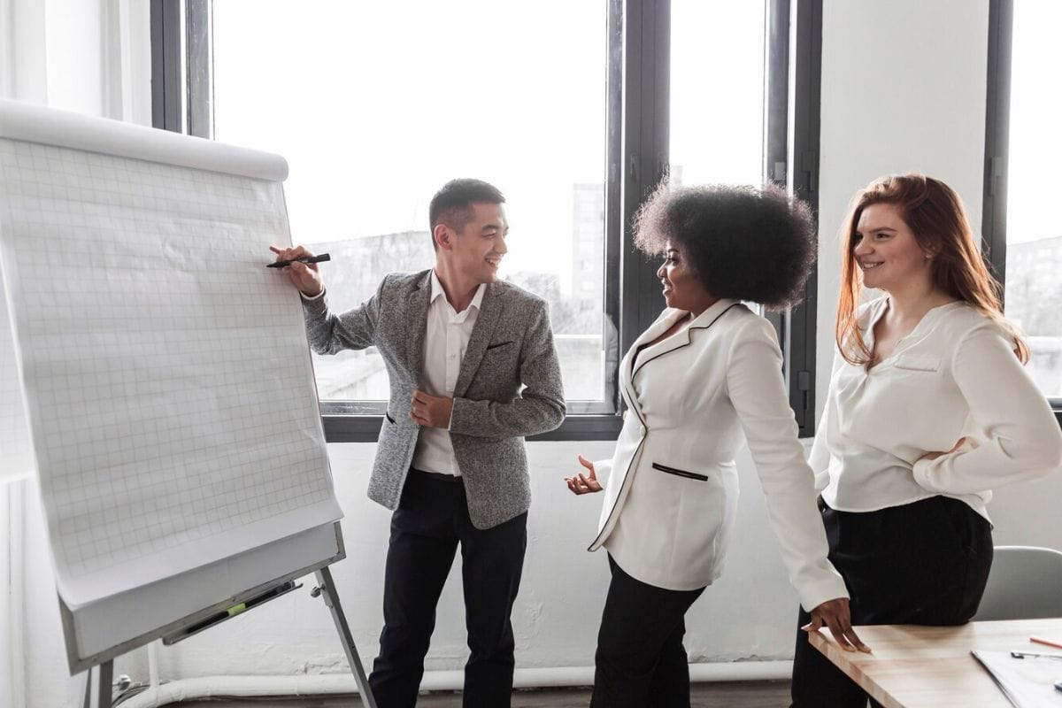 Colleagues discussing ideas at a flipchart in a modern office.