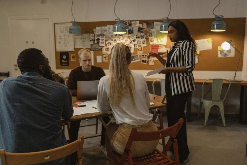 Team collaboration in a cozy workspace, with a woman presenting ideas to her colleagues.
