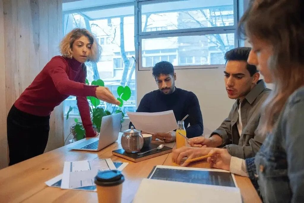 Diverse group of coworkers engaged in a team discussion, analyzing documents and taking notes.