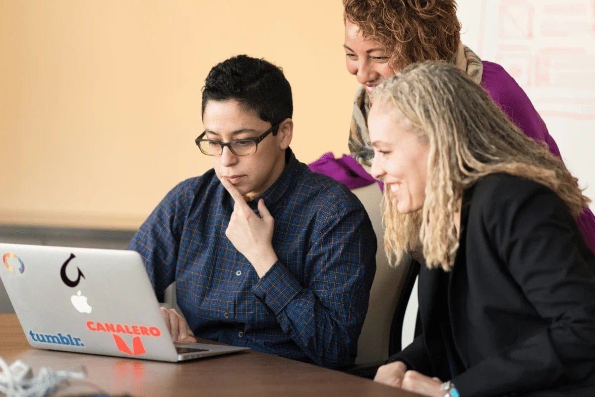 Team of three collaborating around a laptop.