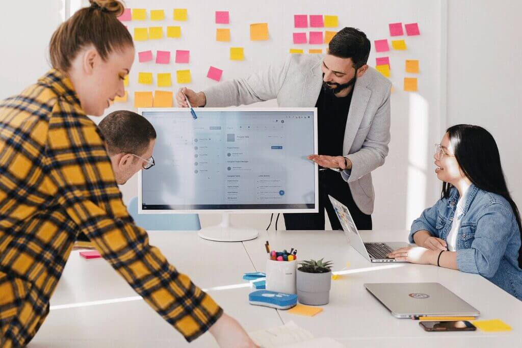 Team collaborating during a meeting with a screen and sticky notes.
