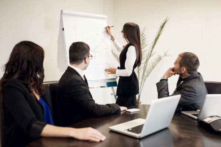 Two professionals engaged in a serious discussion, with documents and a laptop in an office setting.