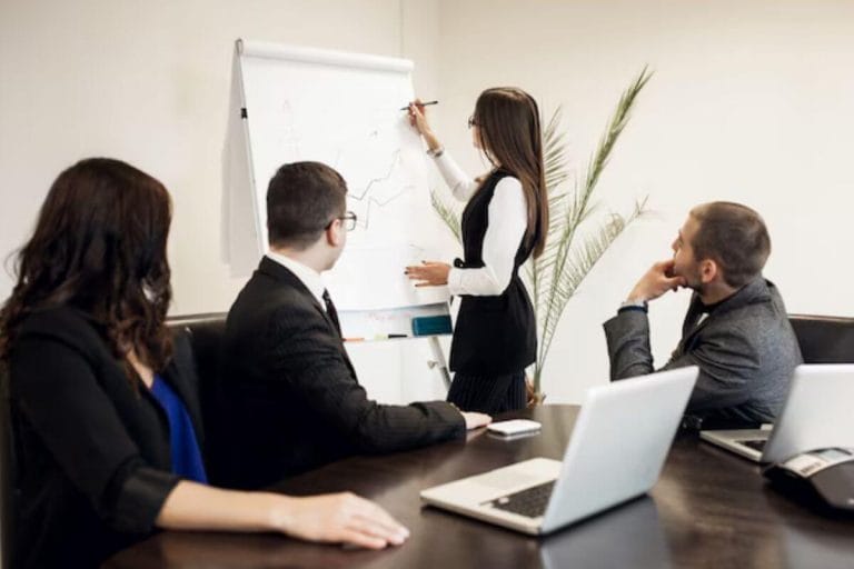 Two professionals engaged in a serious discussion, with documents and a laptop in an office setting.