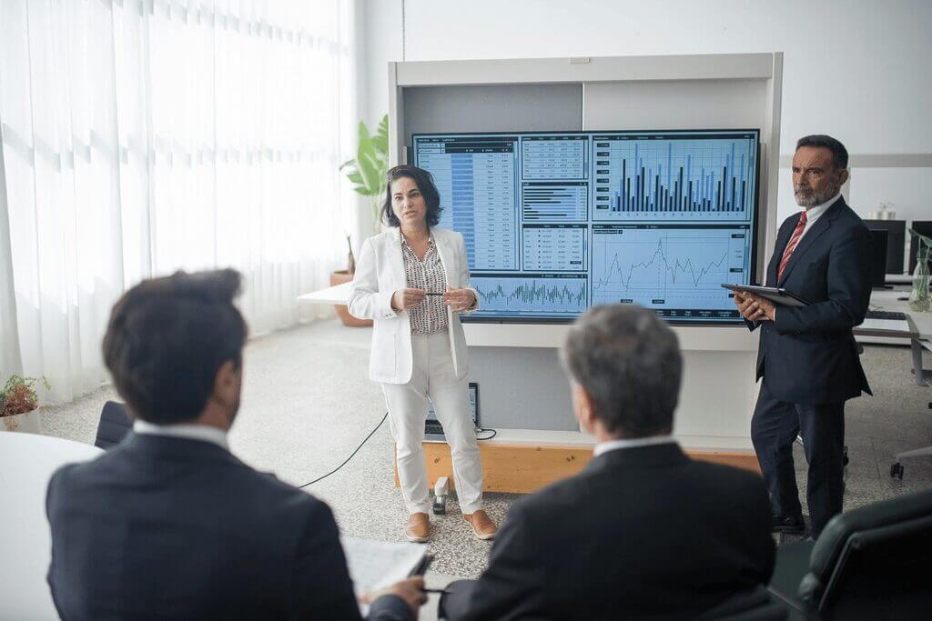 A group of business professionals engaged in a discussion within a modern meeting room setting.