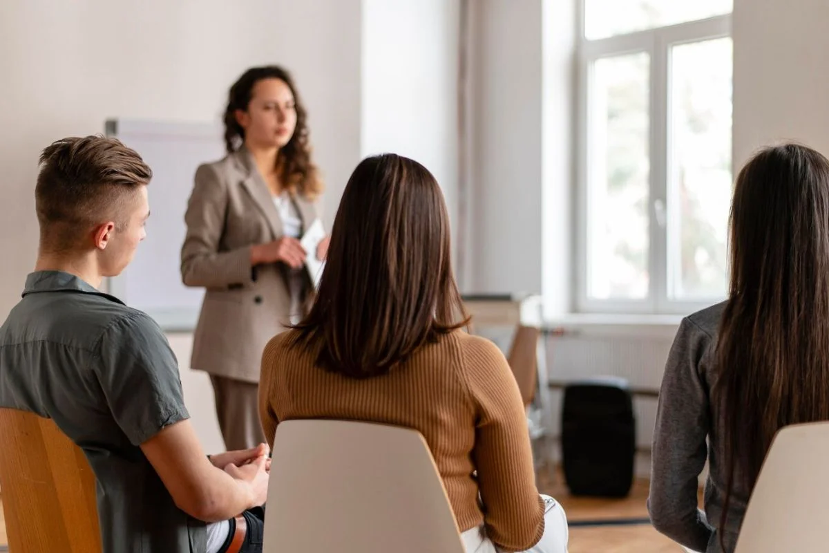 Woman leading a seminar with attentive audience members.