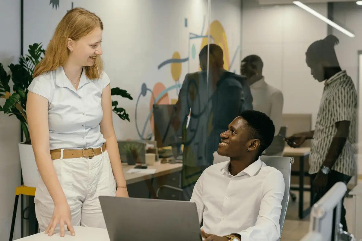 Two colleagues engaging in a friendly conversation in a modern office setting.