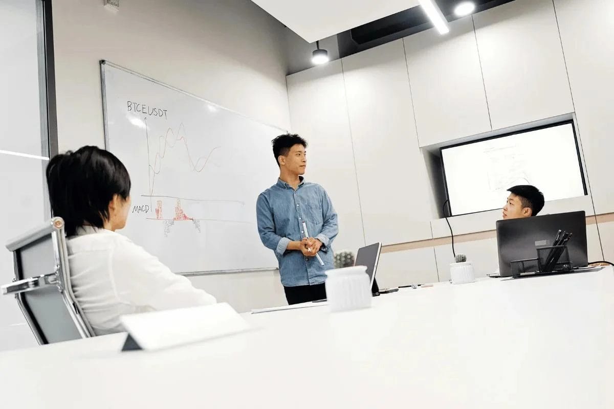 Businessman presenting data on a whiteboard during a meeting in a modern office.