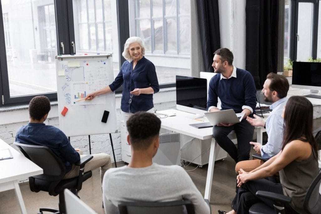A woman presents to an audience, engaging them with her speech and visual aids during a professional meeting.