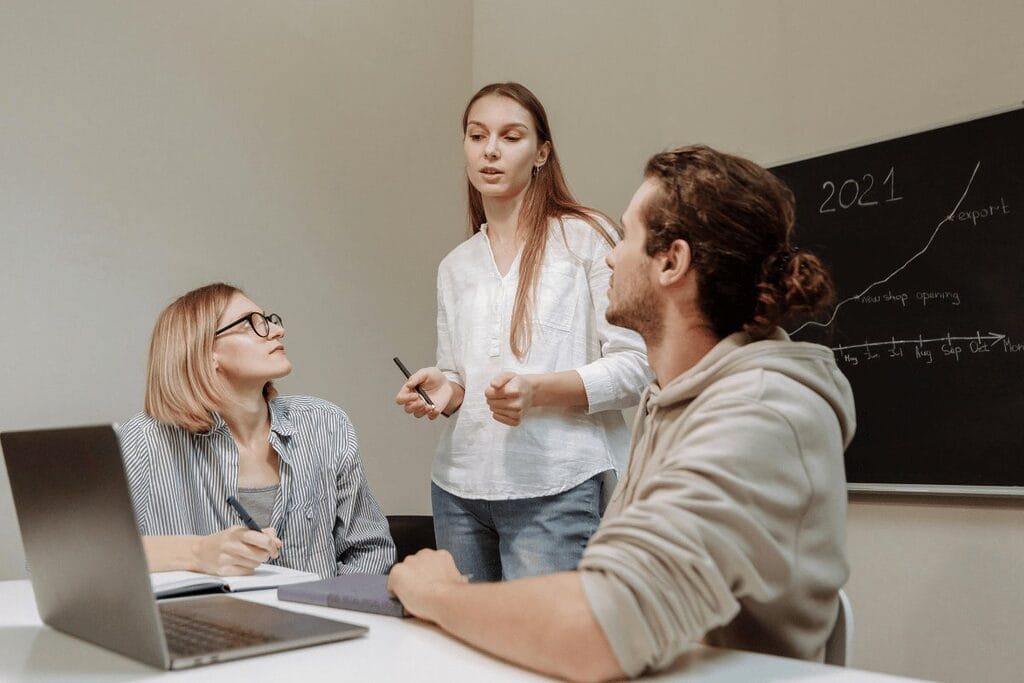 A diverse group of individuals gathered around a table, collaborating with a laptop in the center.