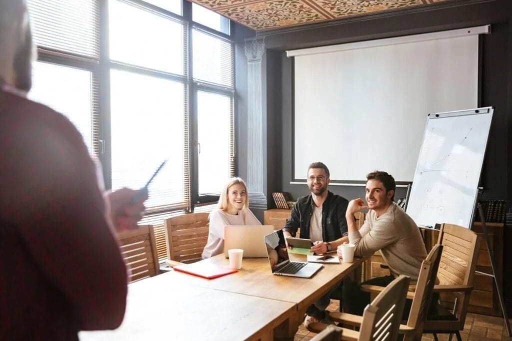 Team meeting in a conference room with a presenter and attentive participants.