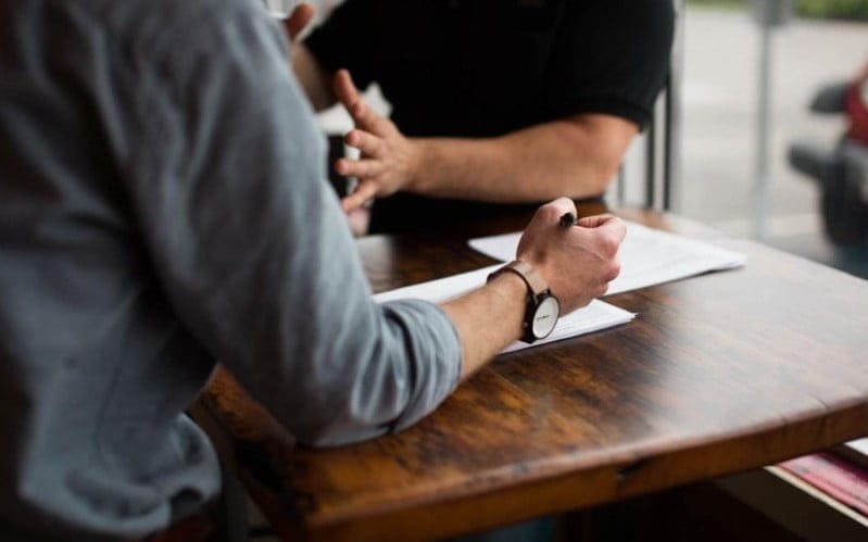 A person holding a pen and collaborating on a project with a colleague.