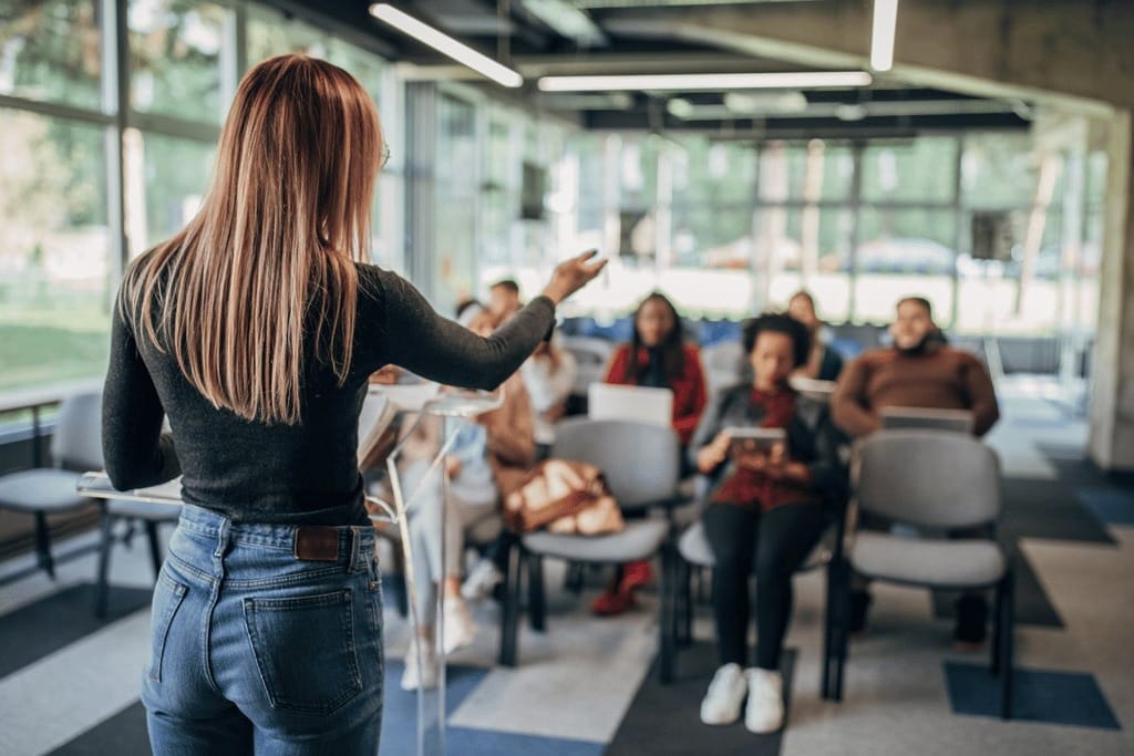 A person presenting to a group in a modern classroom setting.