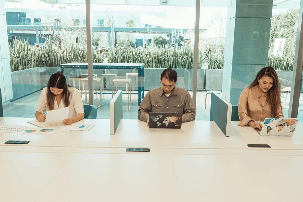 Individuals at a long table, each with a laptop, participating in a collaborative environment or professional discussion.