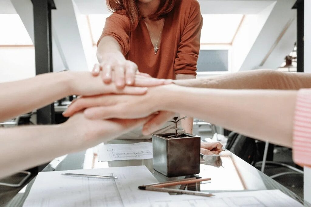 Team members stacking hands in a show of unity.
