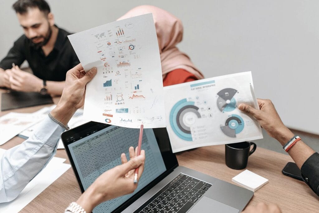 Professionals discussing data charts in a business meeting with a laptop on the table.