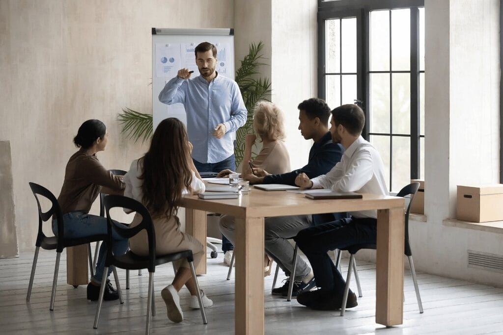 Corporate meeting with a male speaker explaining concepts.