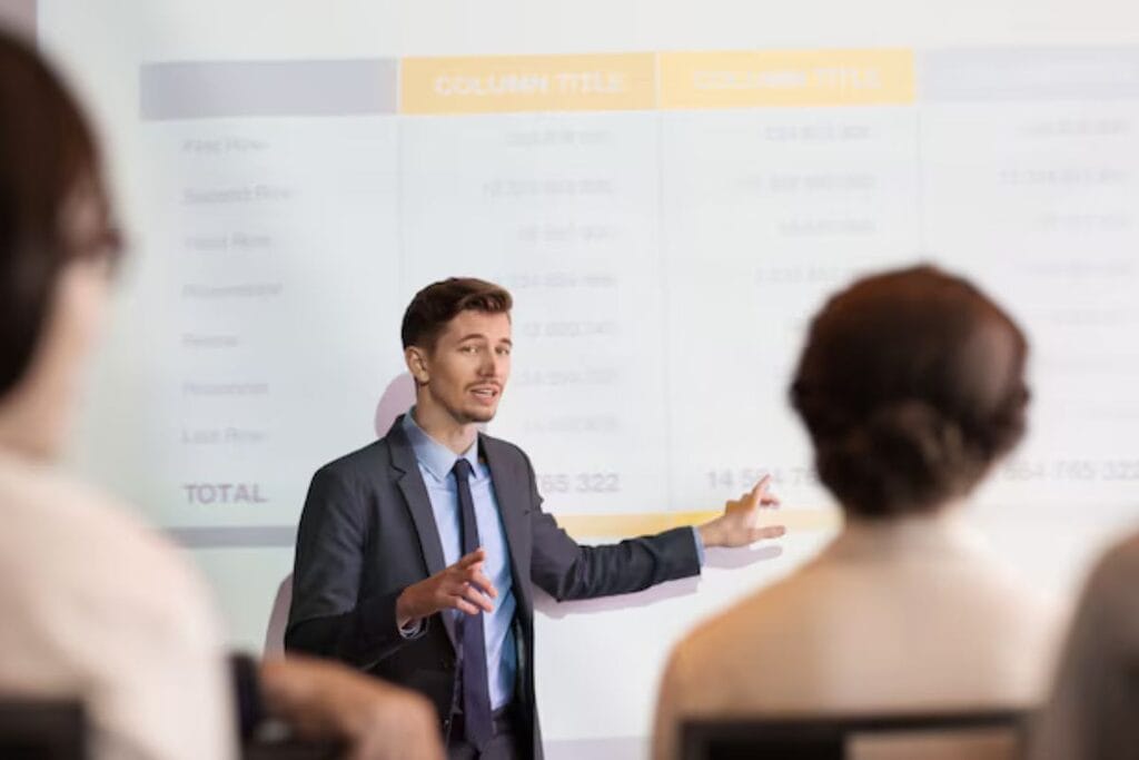 A man presenting a business strategy on a chalkboard to colleagues during a meeting.
