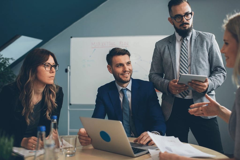 A team of business people in a meeting, focused on a laptop as they share ideas and insights.