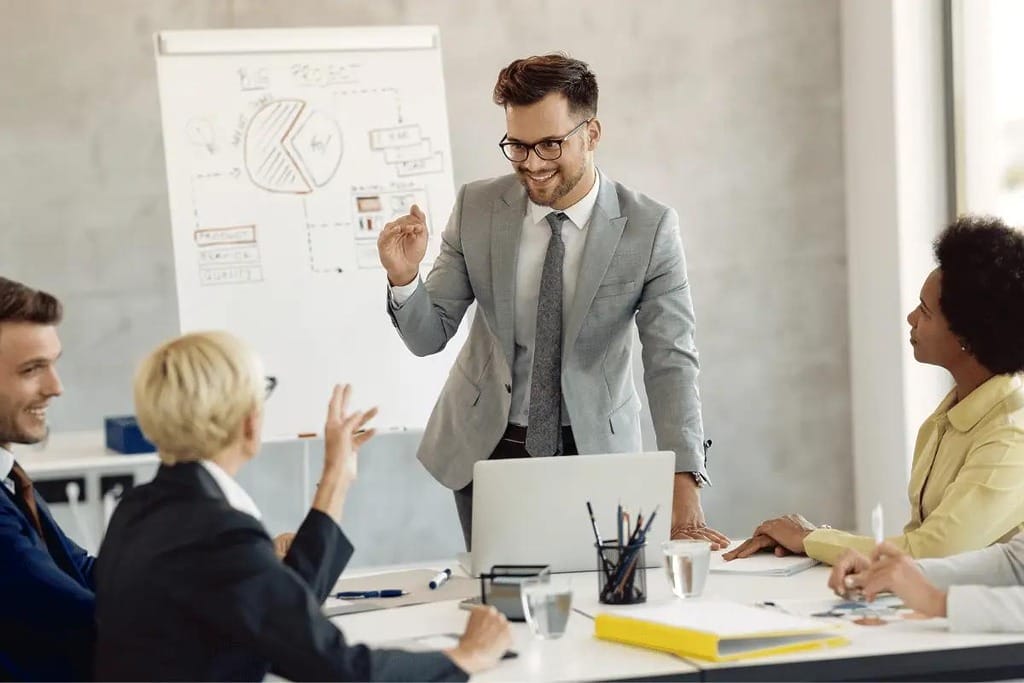 Man in a suit presenting to a team, using a whiteboard to explain the project strategy.
