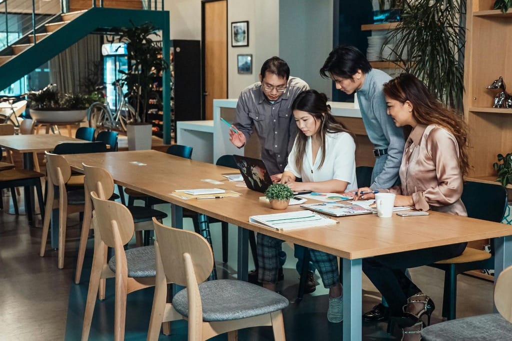 Group of people working together at a table with papers and a laptop in a modern office.