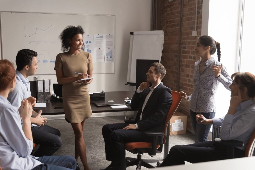 Business meeting with a group of professionals discussing around a whiteboard in an office setting.