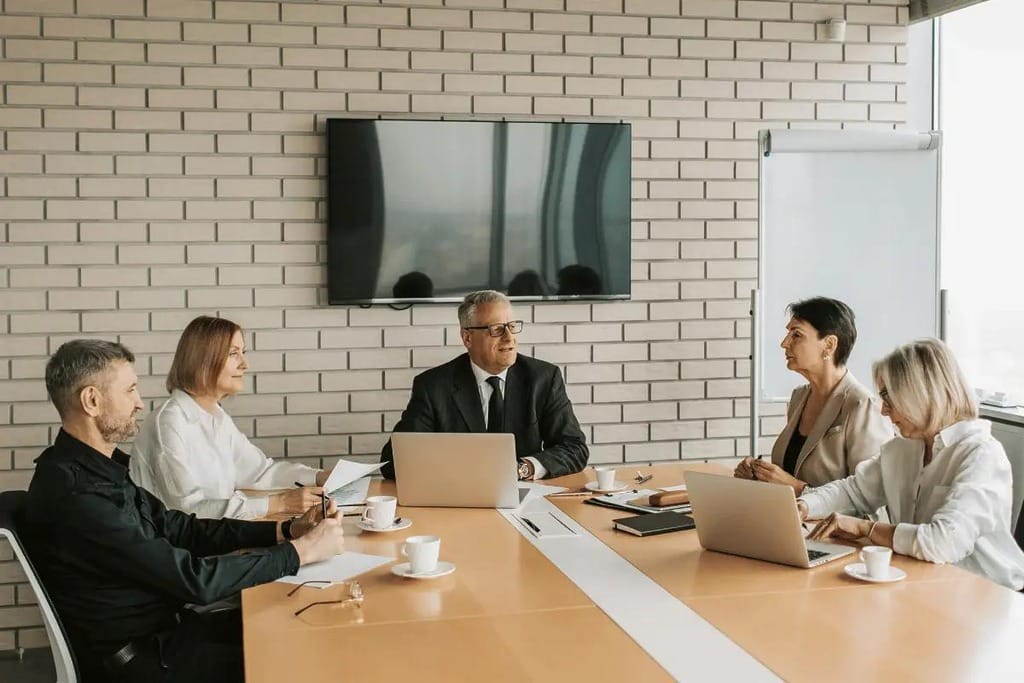 Corporate meeting with senior management in a conference room.
