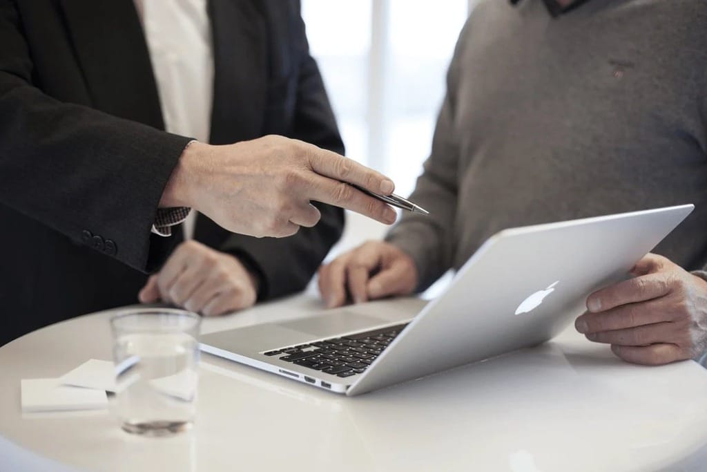Two colleagues discussing work on a laptop in a modern office.