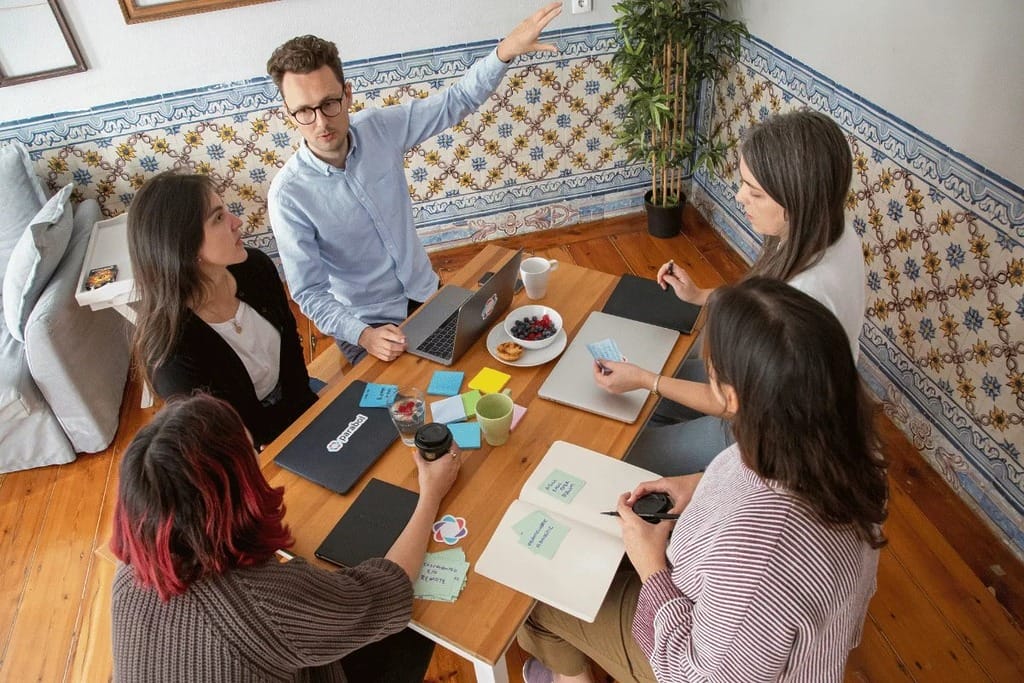 Colleagues engage in a discussion over documents and laptops on the table.
