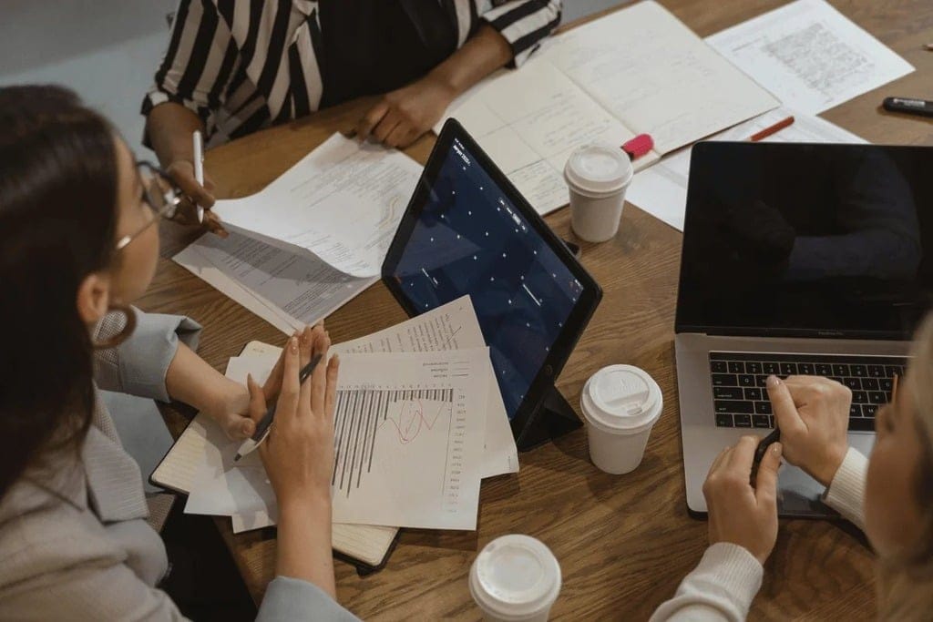 A diverse group of professionals collaborating on a project at a large wooden table.