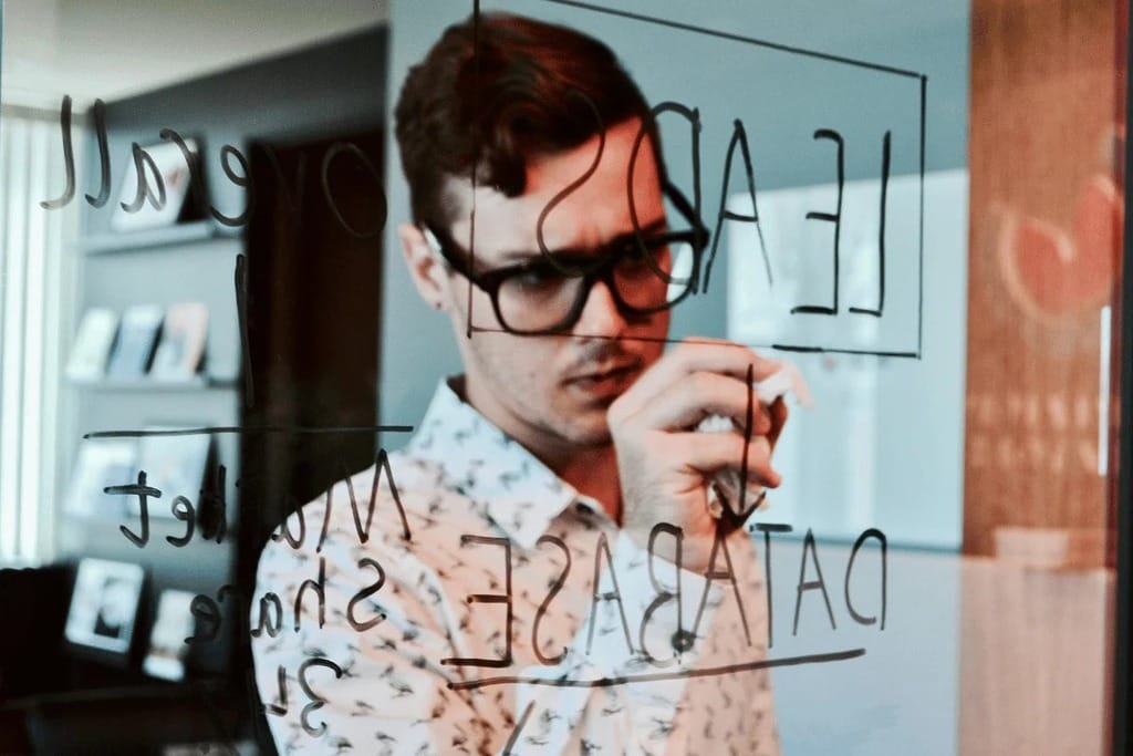 Businessman writing on a glass wall in a modern office.