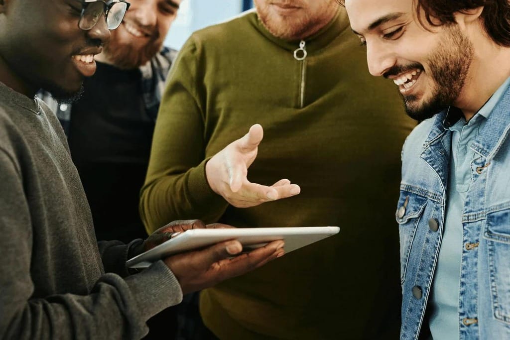 Office workers having a conversation in a bright, industrial-style meeting room.