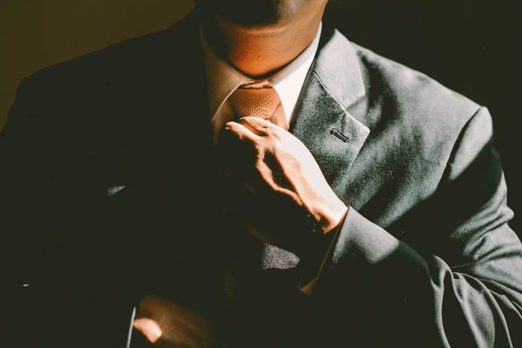 Man in suit and adjusting his tie.