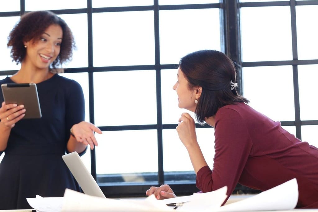 Female coworker explaining something to her colleague with a tablet.
