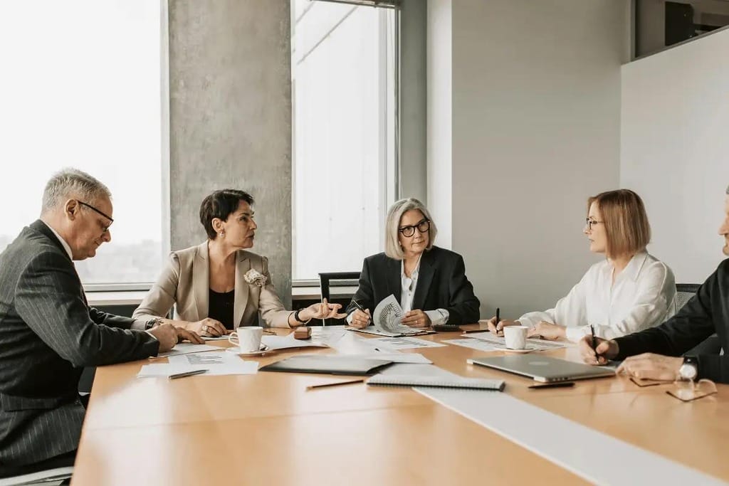 Team of executives reviewing paperwork during a formal meeting in a corporate setting.