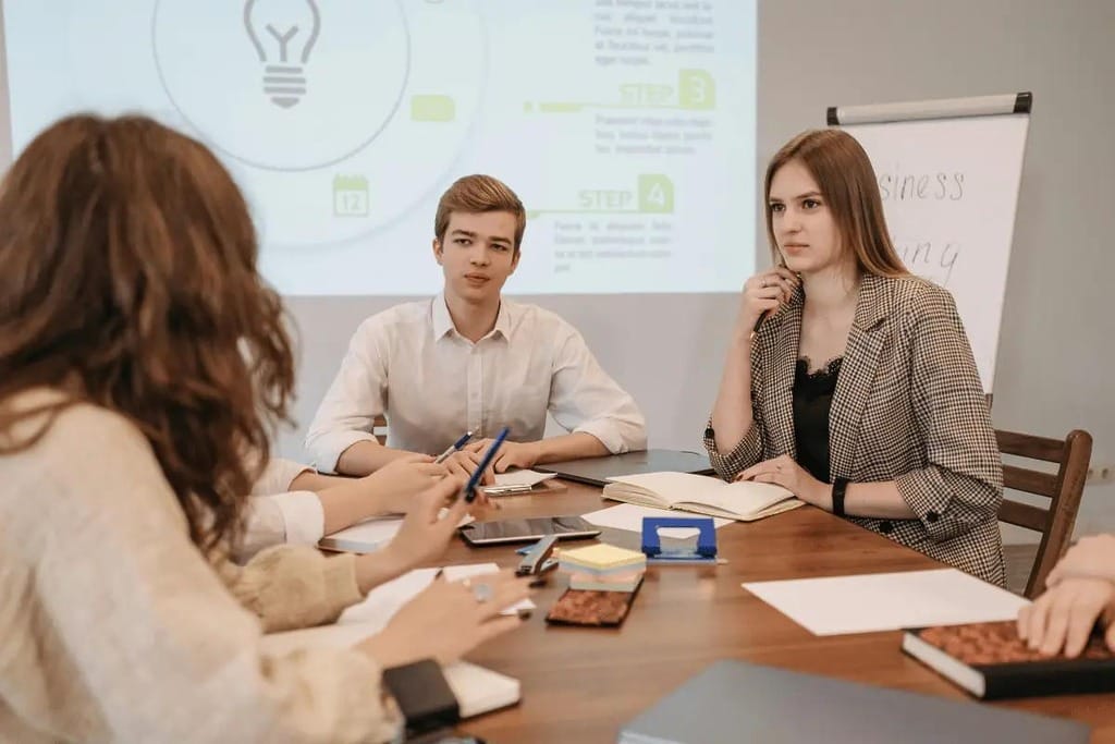 Team members collaborating around a conference table with a presentation in the background.