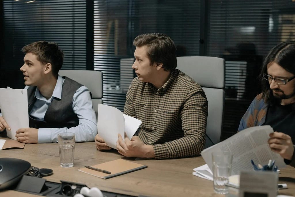 Three team members working together, analyzing documents on a table.