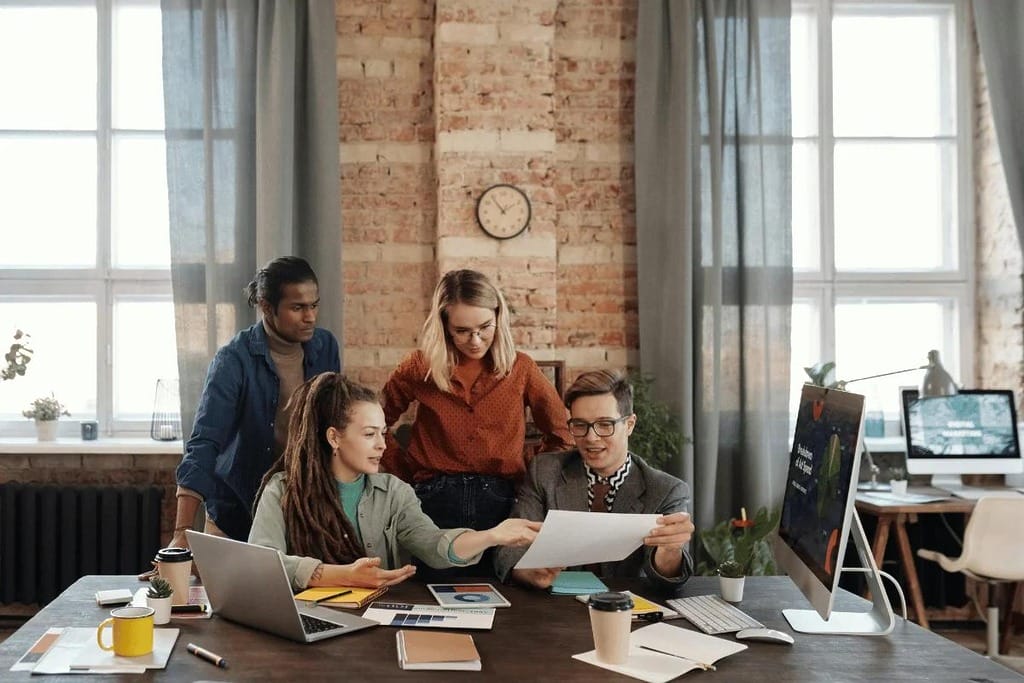 Group of young professionals discussing design ideas at a desk.