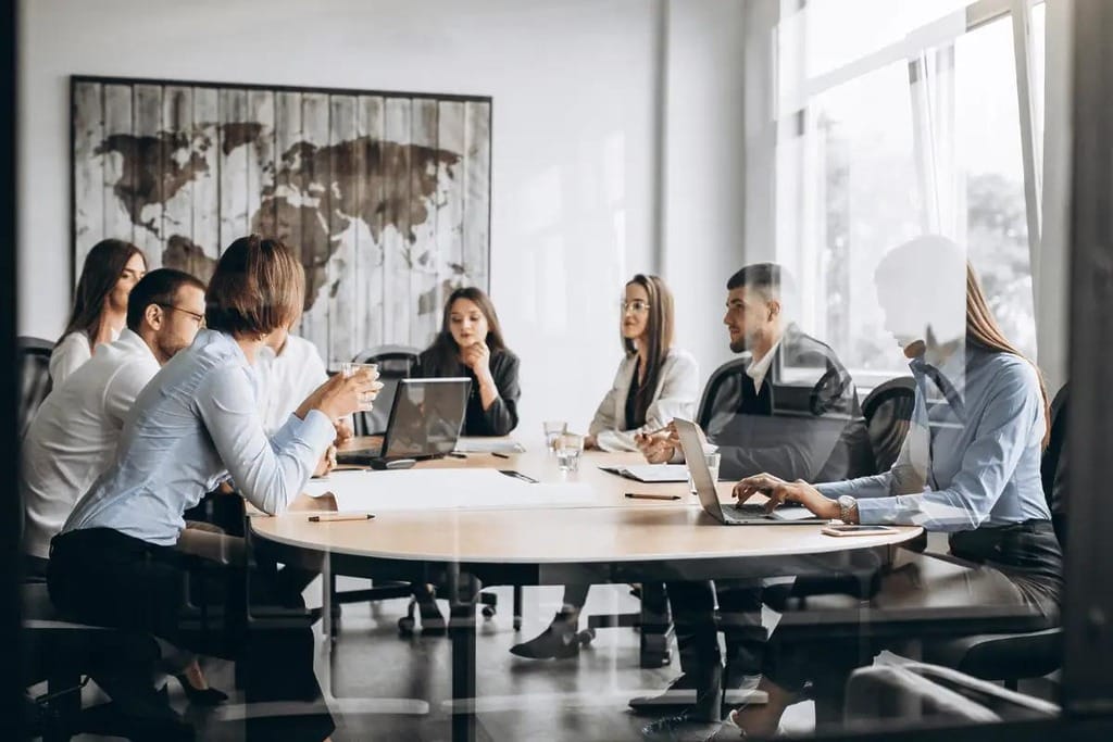 Colleagues engaged in a serious discussion during a team meeting, with laptops and documents spread across the table.