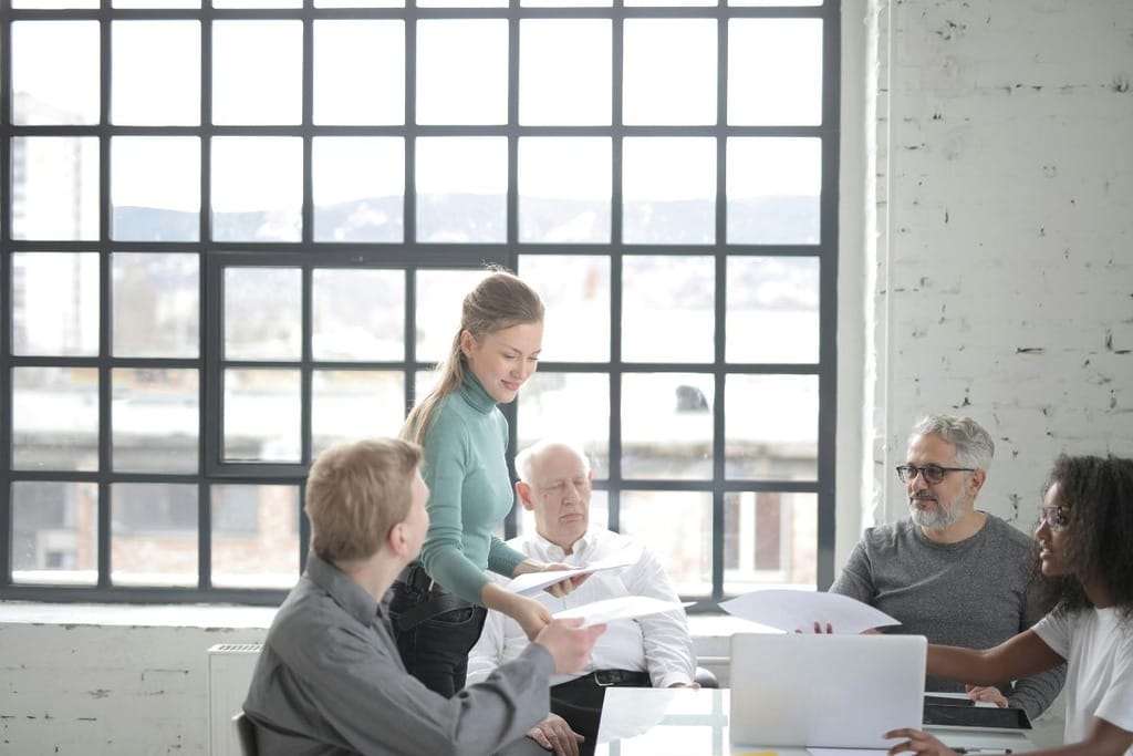 Team meeting in a bright office with large windows and a mountain view outside.