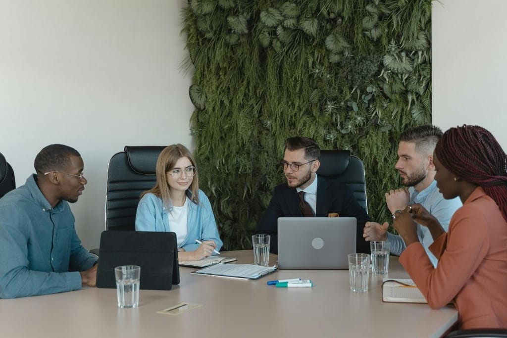 Professionals in a meeting room with a green living wall in the background.