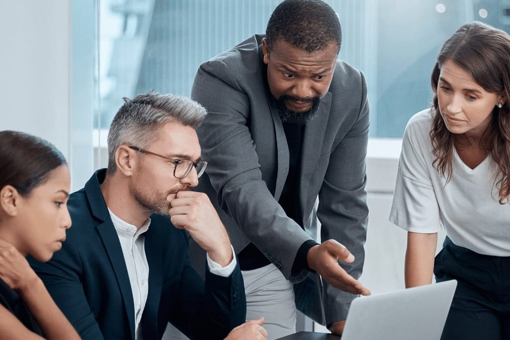 Group of professionals discussing over a laptop in a modern office setting.